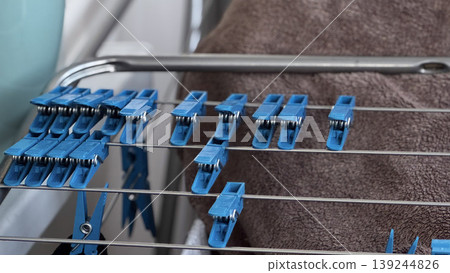 Blue Clothespins on Drying Rack with Soft Towel Background Blue Clothespins on Drying Rack with Soft Towel Background 139244826