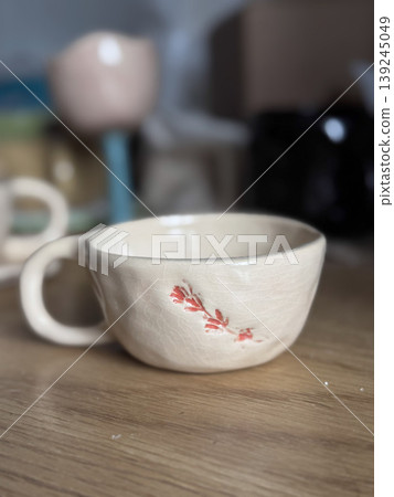 Handcrafted Ceramic Cup with Floral Design on Wooden Table Handcrafted Ceramic Cup with Floral Design on Wooden Table 139245049