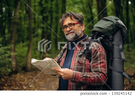 Navigation conception, with map. Hiking experience, senior man is in the forest at daytime Navigation conception, with map. Hiking experience, senior man is in the forest at daytime 139245142