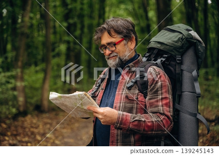 Navigation conception, with map. Hiking experience, senior man is in the forest at daytime 139245143