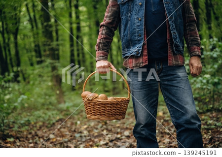 Holding the basket. Close up view of man that is doing mushroom picking in the forest Holding the basket. Close up view of man that is doing mushroom picking in the forest 139245191