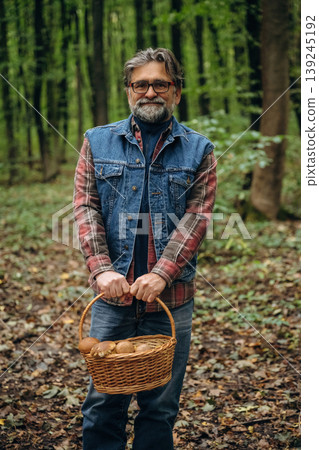 Looking at the camera. Mushroom picking. Man is in the forest at daytime 139245192