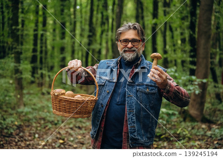 Looking at the camera. Mushroom picking. Man is in the forest at daytime Looking at the camera. Mushroom picking. Man is in the forest at daytime 139245194
