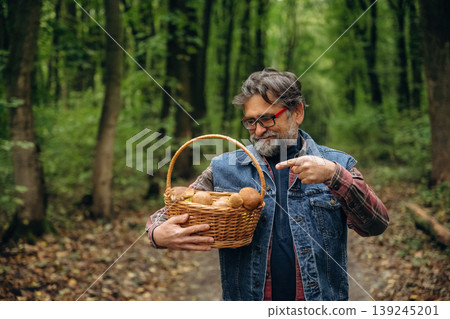 Walking, collected lot of them, in basket. Mushroom picking. Man is in the forest at daytime Walking, collected lot of them, in basket. Mushroom picking. Man is in the forest at daytime 139245201