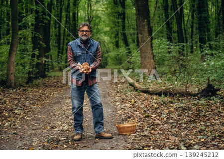 Mushroom picking. Man is in the forest at daytime Mushroom picking. Man is in the forest at daytime 139245212
