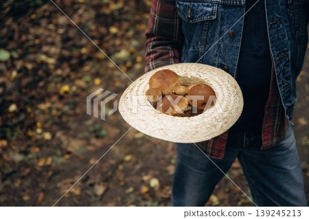 Showing mushrooms, holding them in hands. Close up view of is standing in the forest Showing mushrooms, holding them in hands. Close up view of is standing in the forest 139245213