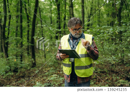 Quality control, with notepad. Senior forest ecologist is working in the woods. In the uniform Quality control, with notepad. Senior forest ecologist is working in the woods. In the uniform 139245235