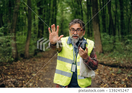 Stop hand gesture, no trespassing. Senior forest ecologist is working in the woods. In the uniform 139245247