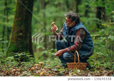 Identification if it's safe one. Mushroom picking. Man is in the forest at daytime Identification if it's safe one. Mushroom picking. Man is in the forest at daytime 139245338