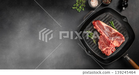 Raw porterhouse t-bone steak on grill pan with herbs and spices on dark background with copy space for bbq advertising Raw porterhouse t-bone steak on grill pan with herbs and spices on dark background with copy space for bbq advertising 139245464