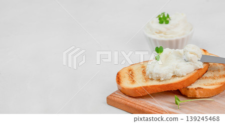 Spreading cream cheese on toasted bread with knife, breakfast concept with copy space 139245468