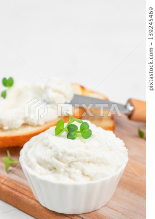 Cream cheese in white bowl with microgreens and toast in background, close up Cream cheese in white bowl with microgreens and toast in background, close up 139245469