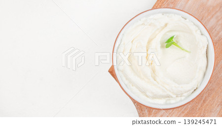 Cream cheese in bowl with microgreens on wooden board, soft spread texture, minimal food background with copy space 139245471