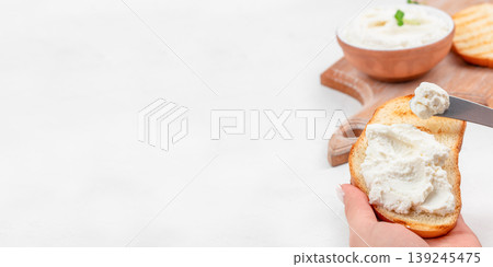 Hand spreading cream cheese on toast with knife breakfast food concept copy space Hand spreading cream cheese on toast with knife breakfast food concept copy space 139245475
