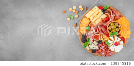 Gourmet charcuterie board with cheese prosciutto olives fruits and crackers on concrete background with copy space Gourmet charcuterie board with cheese prosciutto olives fruits and crackers on concrete background with copy space 139245516