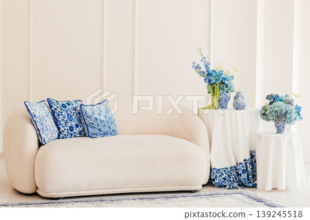 Elegant beige sofa with blue pillows and floral decor in bright living room interior with copy space Elegant beige sofa with blue pillows and floral decor in bright living room interior with copy space 139245518