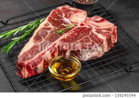 Raw porterhouse t-bone steak on grill rack with oil and herbs close up for premium meat and bbq cooking concept Raw porterhouse t-bone steak on grill rack with oil and herbs close up for premium meat and bbq cooking concept 139245544