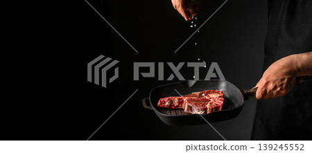 Chef seasoning raw steak with salt over grill pan on black background. copy space Chef seasoning raw steak with salt over grill pan on black background. copy space 139245552