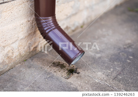 Homeowner checks drain for deterioration. Evaluating moss and rust on drainage outlet 139246263