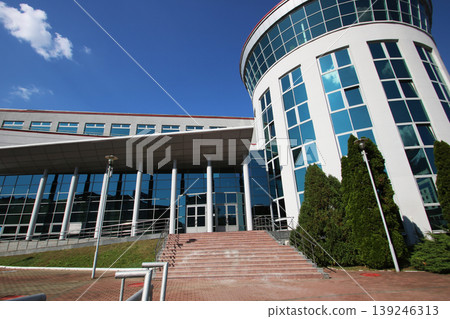 Sophisticated corporate edifice with reflective surfaces and structured landscaping Sophisticated corporate edifice with reflective surfaces and structured landscaping 139246313