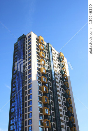 A tall building stands with a beautiful blue sky in the background 139246330