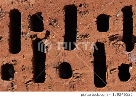 Close-up of a red clay brick showing vertical perforations Close-up of a red clay brick showing vertical perforations 139246525