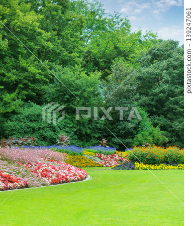 Beautiful Landscaped Park with Vibrant Flower Beds and Green Lawn 139247061