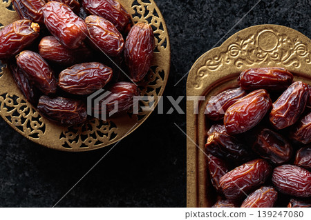 Dates fruits in a golden bowls on black stone table. 139247080