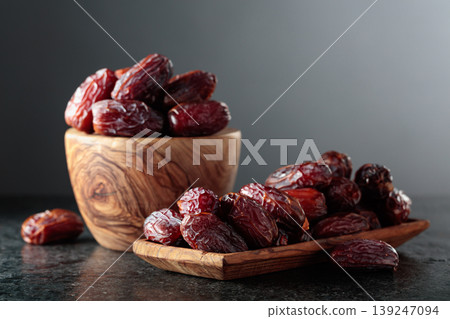 Dates fruit in wooden dish on a black table. Dates fruit in wooden dish on a black table. 139247094