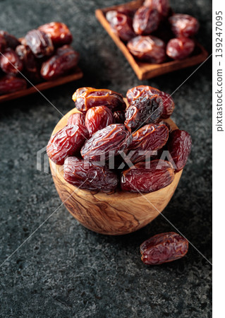 Dried dates fruit in wooden bowl on a black table. 139247095