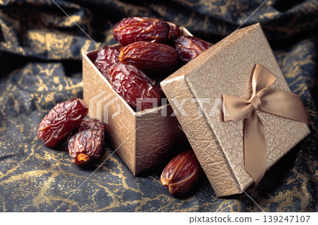 Dates in a gift box on black fabric with gold ornamentation. 139247107