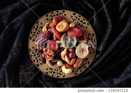 Dried tropical fruits and nuts in a golden bowl. Dried tropical fruits and nuts in a golden bowl. 139247110