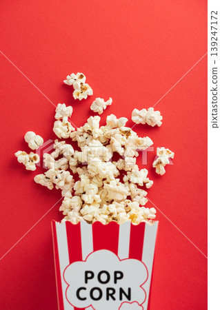 Popcorn  in white striped paper box  and spill on Red Background 139247172