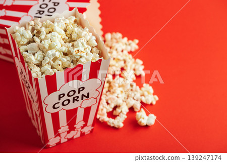Popcorn in white striped paper boxes and spill on Red Background Popcorn in white striped paper boxes and spill on Red Background 139247174