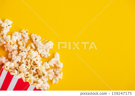 Popcorn in white striped paper box and spill on Yellow Background Popcorn in white striped paper box and spill on Yellow Background 139247175