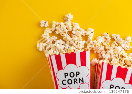 Popcorn in white striped paper boxes and spill on Yellow Background Popcorn in white striped paper boxes and spill on Yellow Background 139247176