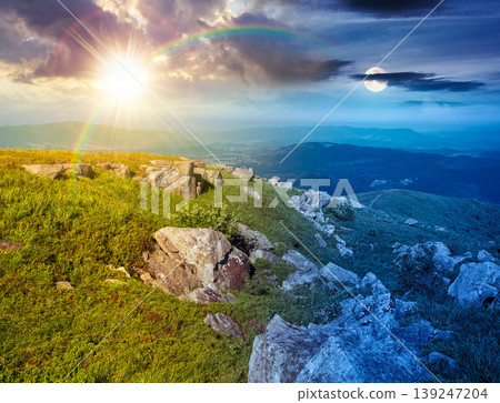 day meet night in mountain landscape with stones and grass. view of mountains on summer solstice. sun and moon over white sharp stones on the rolling hills on top of mountain range under epic sky 139247204