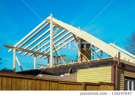 Timber roof frame under construction on house renovation project with blue sky background scene Timber roof frame under construction on house renovation project with blue sky background scene 139247647