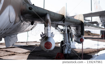 Underwing Pylons And Rocket Pods Grounded. Weathered Bomber Parked On Sunlit Tarmac With Visible Mounting Hardware, Service Cables, And Chocks Closeup Perspective Emphasizes Pylon Structure, 139247961