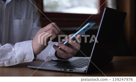 Authorizing Payment On Smartphone Beside Laptop, White Shirt Sleeve Visible, Secure Authentication And Verification, Closeup Of Hands Confirming Transaction And Twofactor Prompts, Modern Authorizing Payment On Smartphone Beside Laptop, White Shirt Sleeve Visible, Secure Authentication And Verification, Closeup Of Hands Confirming Transaction And Twofactor Prompts, Modern 139247976