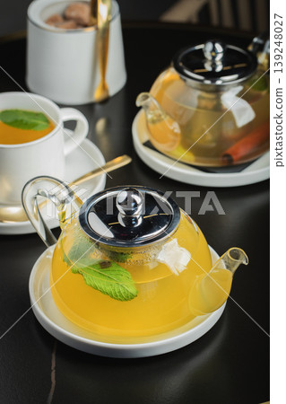 Fruit tea with mango and mint in a glass teapot on the table Fruit tea with mango and mint in a glass teapot on the table 139248027