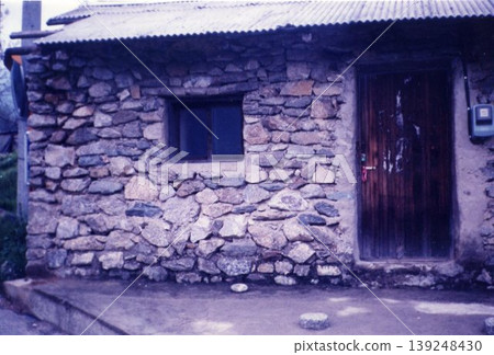 Stone House Exterior with Weathered Walls and Wooden Door 139248430