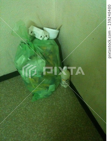Green Plastic Bag with Items in Corner 139248480
