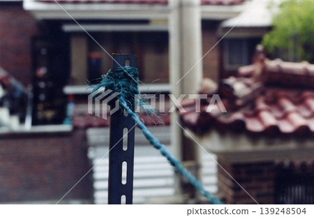 Blue Rope Tied to Metal Post with House Background 139248504