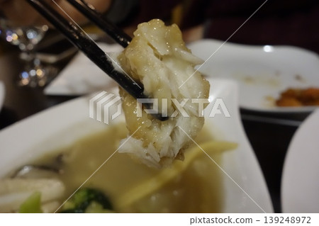 Chopsticks Holding Steamed Dumpling Over Soup Dish Chopsticks Holding Steamed Dumpling Over Soup Dish 139248972
