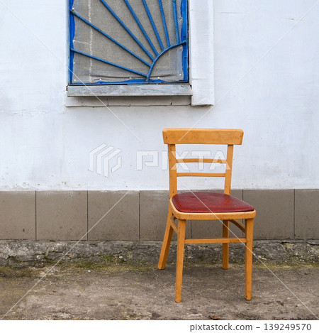 yellow chair against a white wall with a blue window yellow chair against a white wall with a blue window 139249570