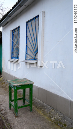 green stool near a building wall with grilles green stool near a building wall with grilles 139249572