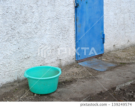 turquoise basin on the ground near a blue door turquoise basin on the ground near a blue door 139249574