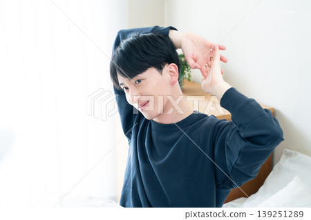 A young man stretching in bed A young man stretching in bed 139251289