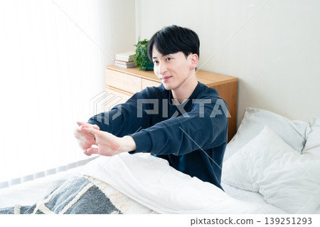 A young man stretching in bed A young man stretching in bed 139251293